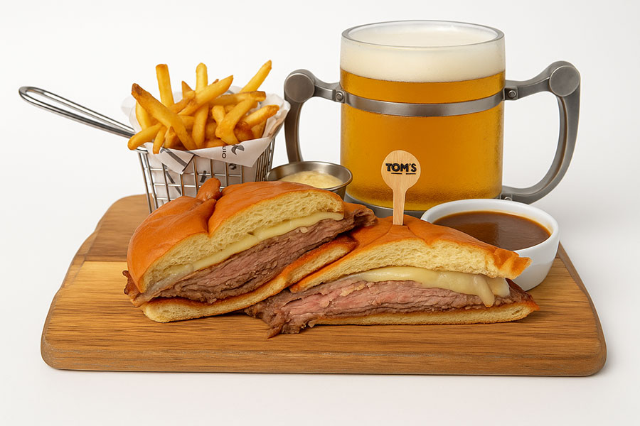 prime rib sandwich with fries and a draft beer