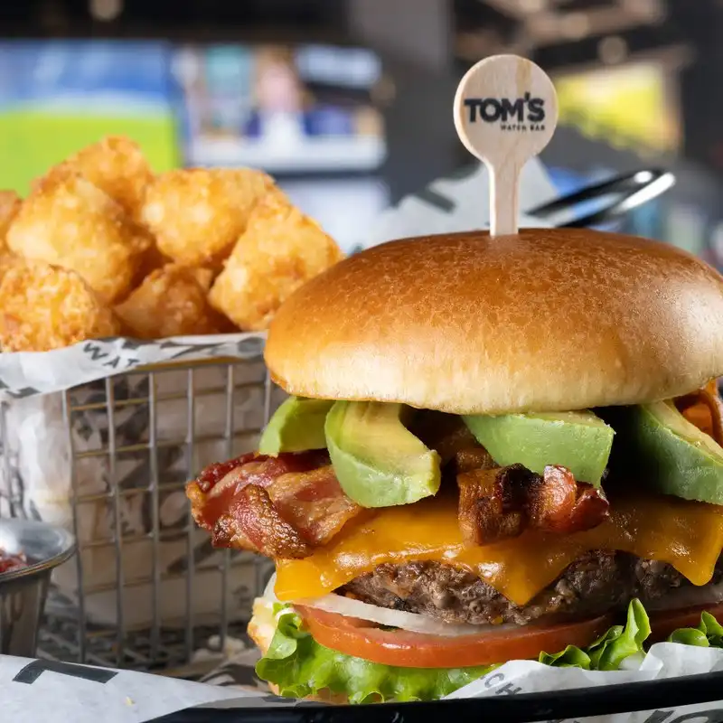 Bacon Avocado Burger with Tater Tots Bacon avocado cheeseburger with a side of tater tots at Tom's Watch Bar